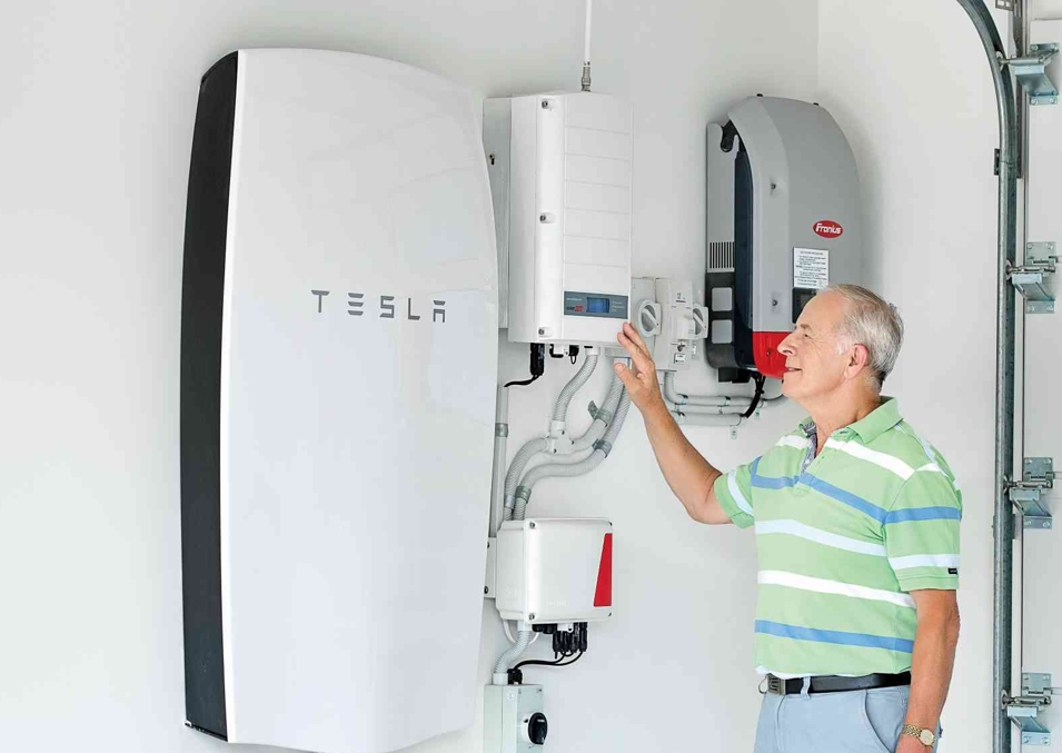 Homeowner inspecting their Tesla battery installed in the garage of their home at a Stockland Halcyon community