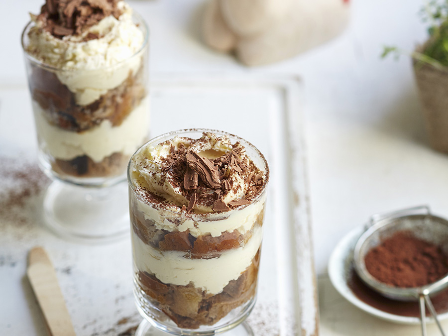 Tiramisu hot cross buns served in a glass cup with cocoa sprinkled on top. 