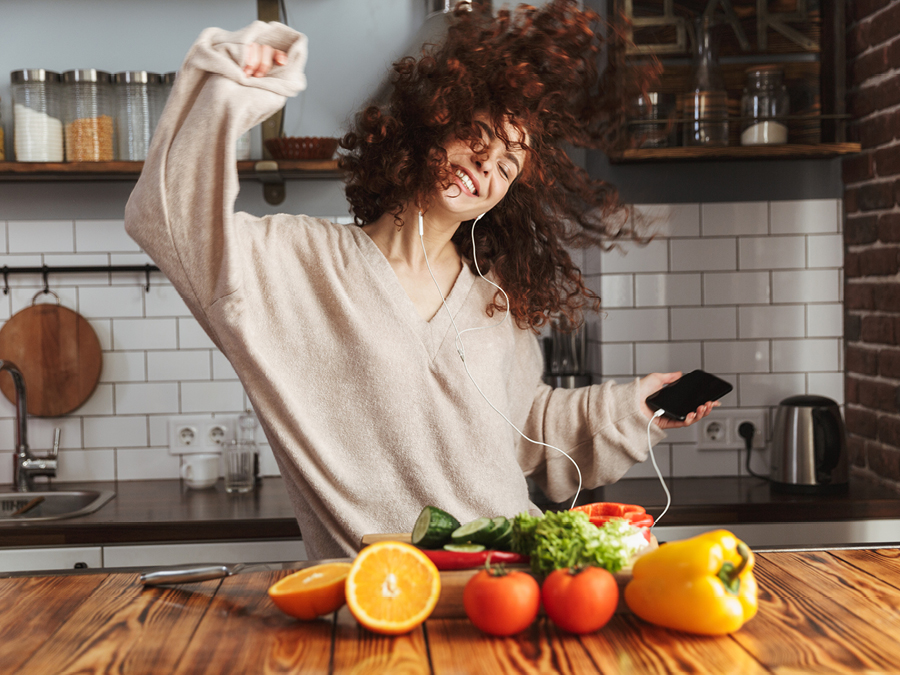 A woman listening and dancing to music on her phone device in the kitchen