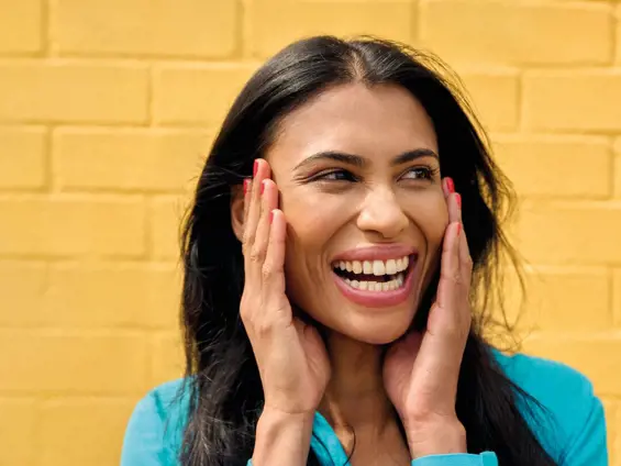 A woman laughing while holding her face with both hands