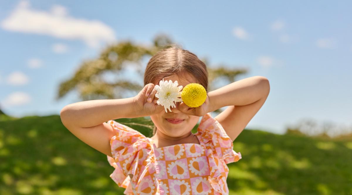 A young girl covering her eyes with flowers