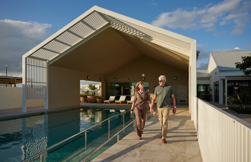Couple walking hand in hand next to the Halcyon Nirimba pool