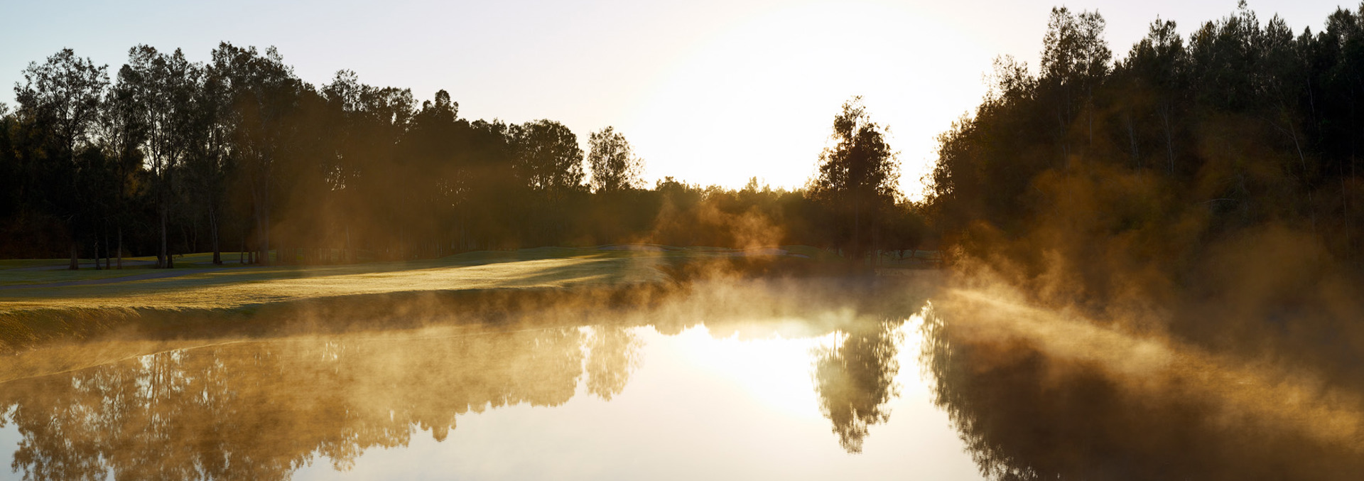 Photo of Gainsborough Greens golf course lake with sun reflection on water and steam coming off the lake