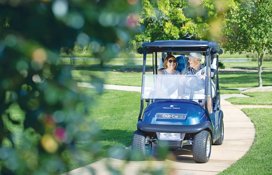 Man and woman on golf buggy heading down a pathway surrounded by green space