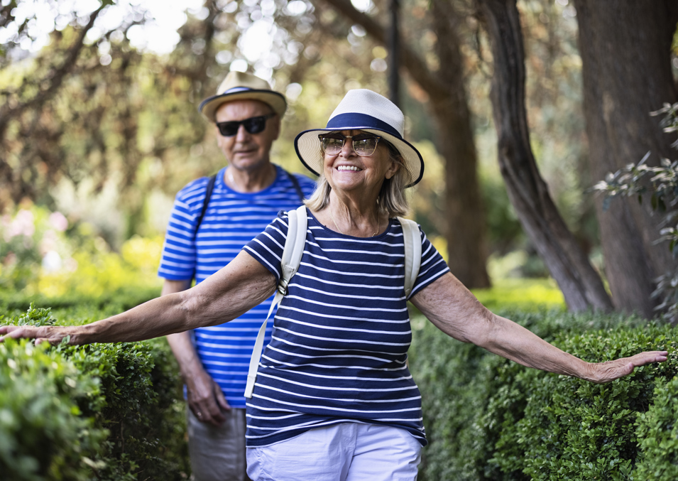 Couple smiling and walking through bushland with hedges