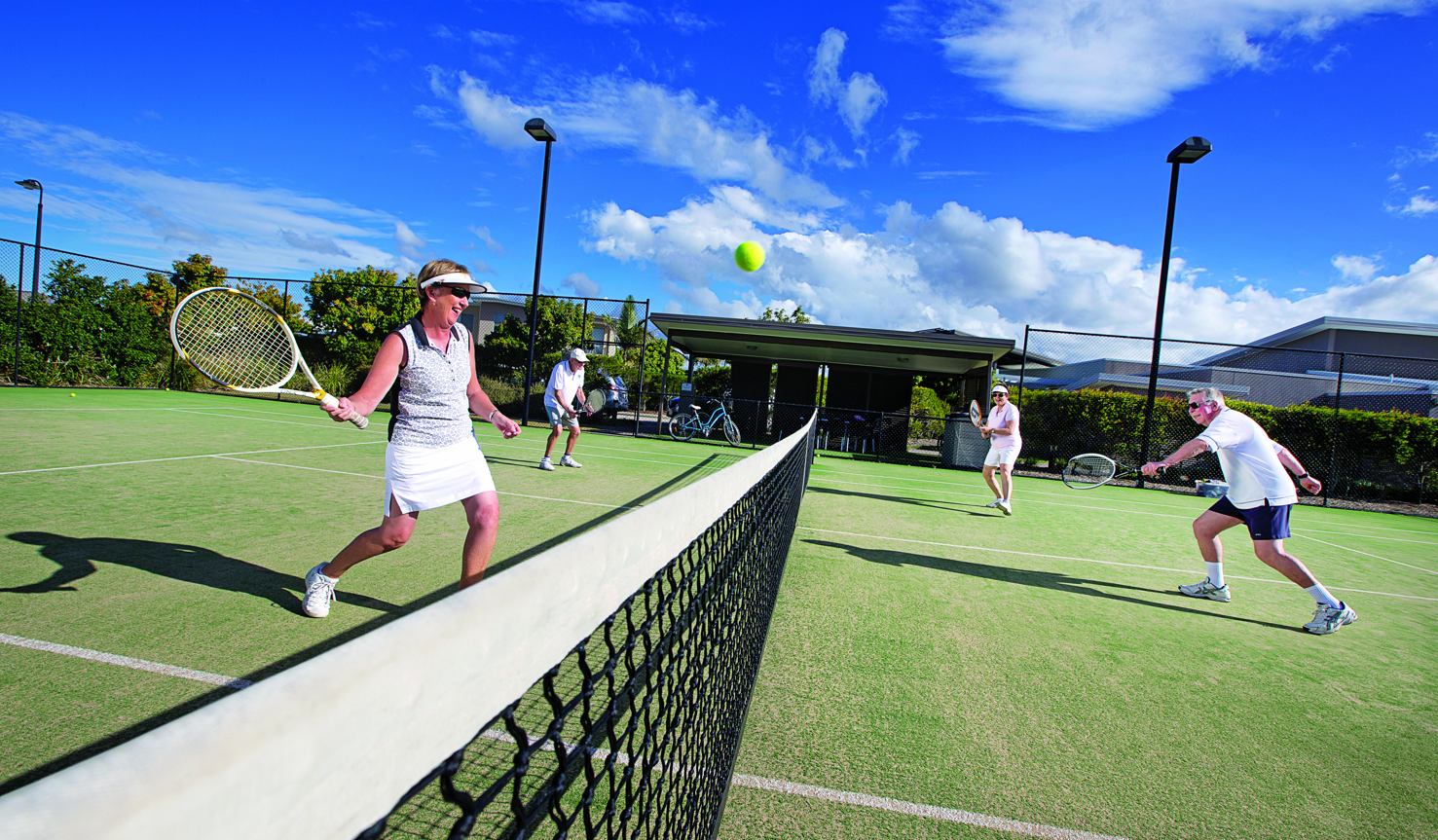 Action shot of couples playing tennis on the Halcyon Waters tennis court