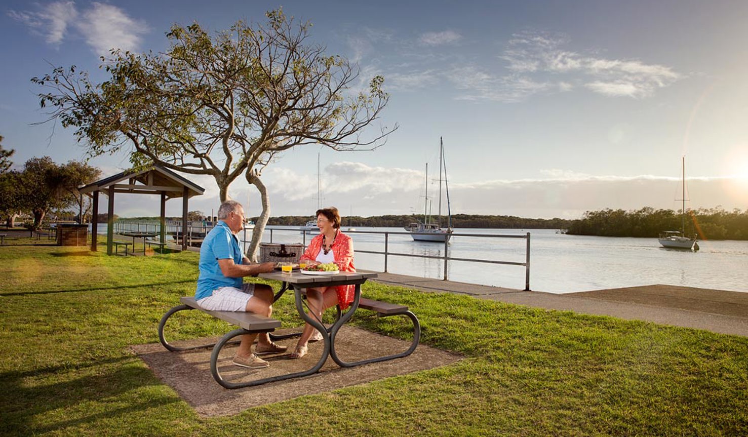 Couple sitting at a park bench by the water at Hope Island