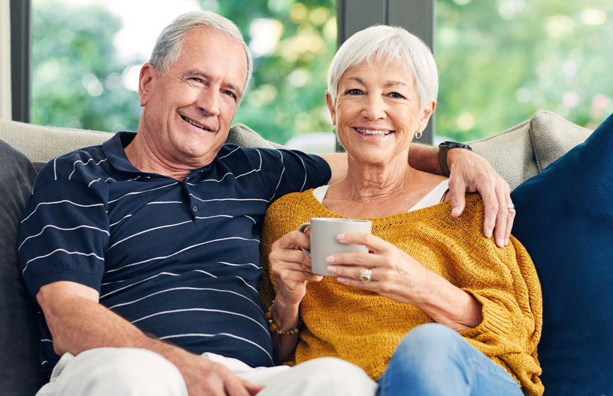 Man and woman sitting down on the couch holding a mug.