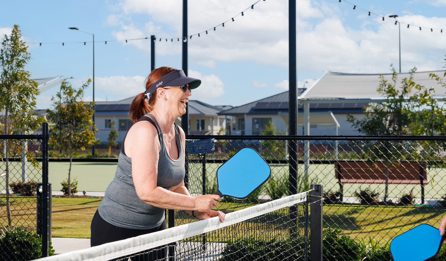 A lady in her 60s holding a pickleball racket at the pickleball court at Halcyon Rise.
