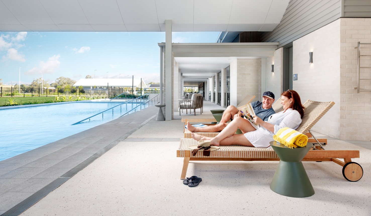 A couple sitting by the pool reading a magazine at Halcyon Rise.