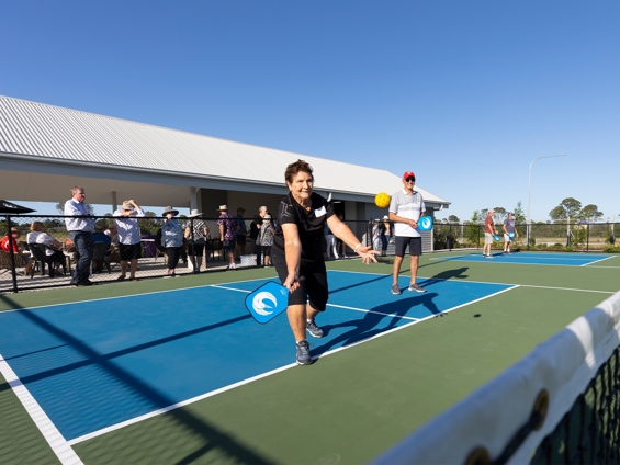 A lady aiming to hit the ball while playing pickleball. 