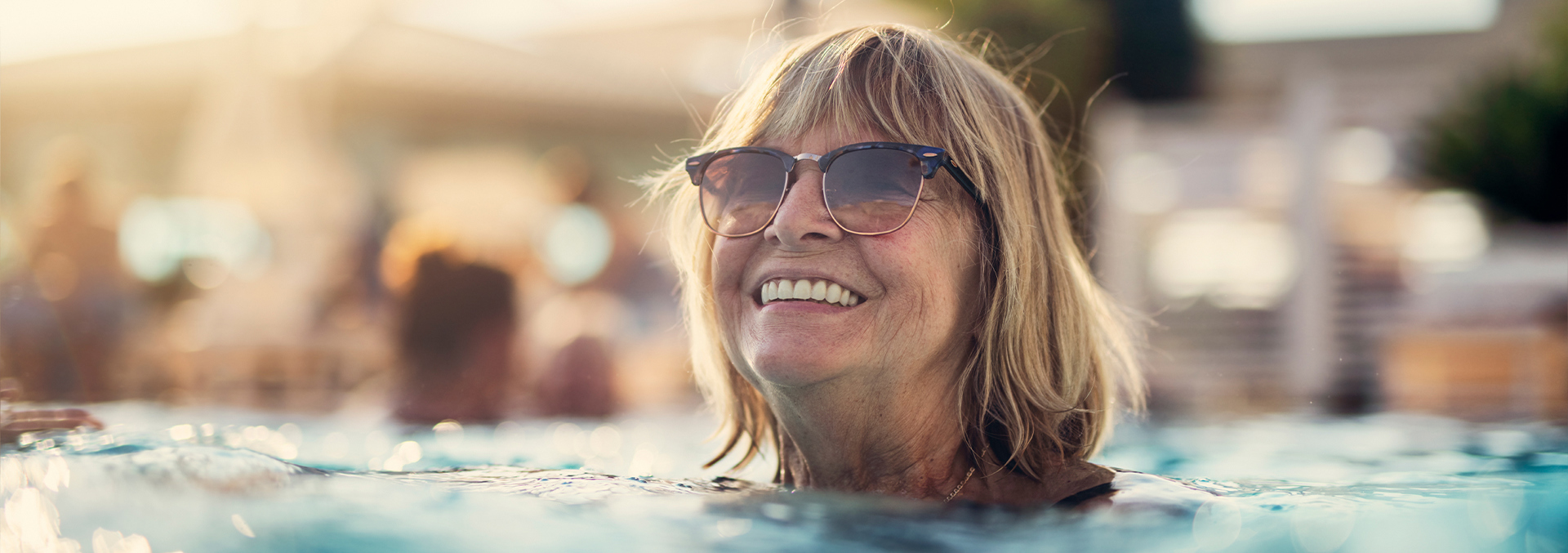 A lady swimming in the pool and smiling.