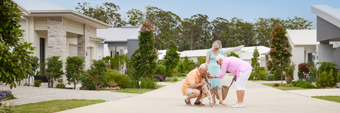 group of three people over 50 gather together on a quiet street to pat a dog