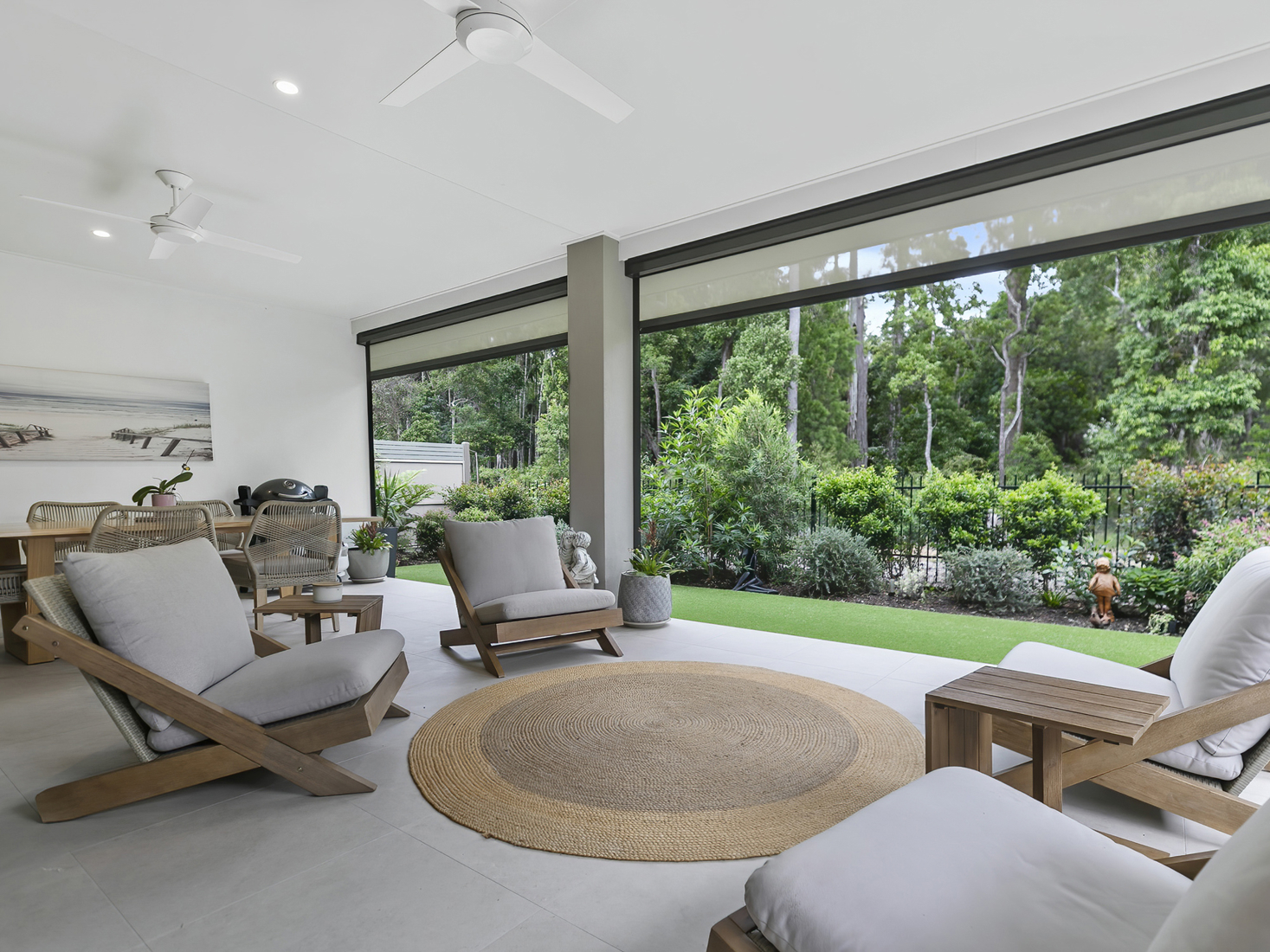Outdoor covered patio with modern timber lounge setting overlooking lush green garden