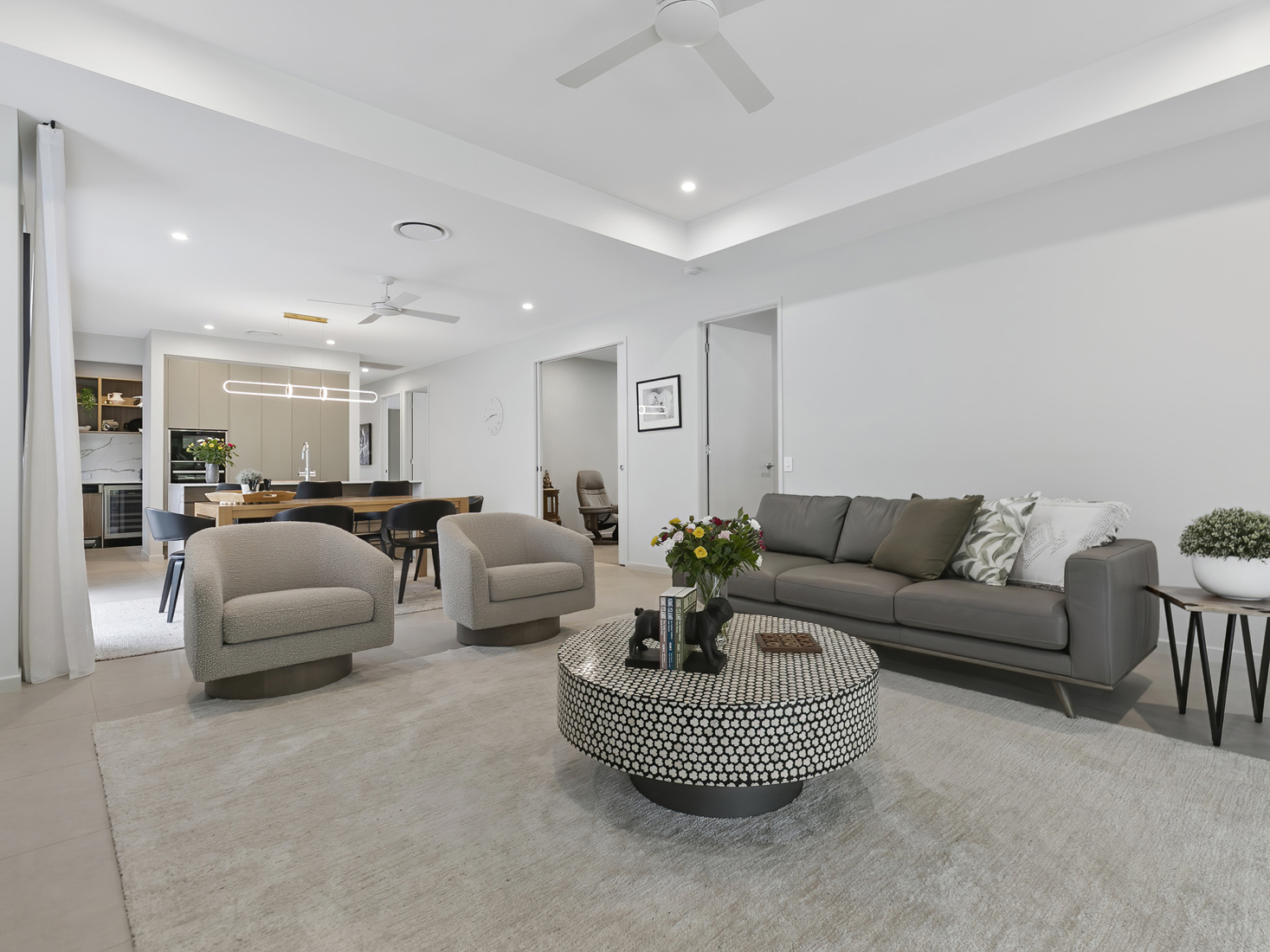 open plan living and dining space with grey sofa and two singular armchairs, with modern styling.