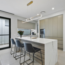 modern white and light beige open plan kitchen with island bench and modern pendant light.