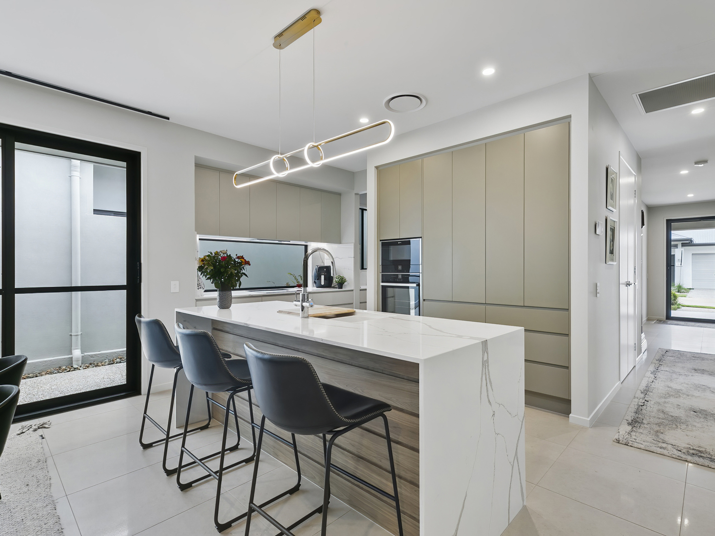 modern white and light beige open plan kitchen with island bench and modern pendant light.