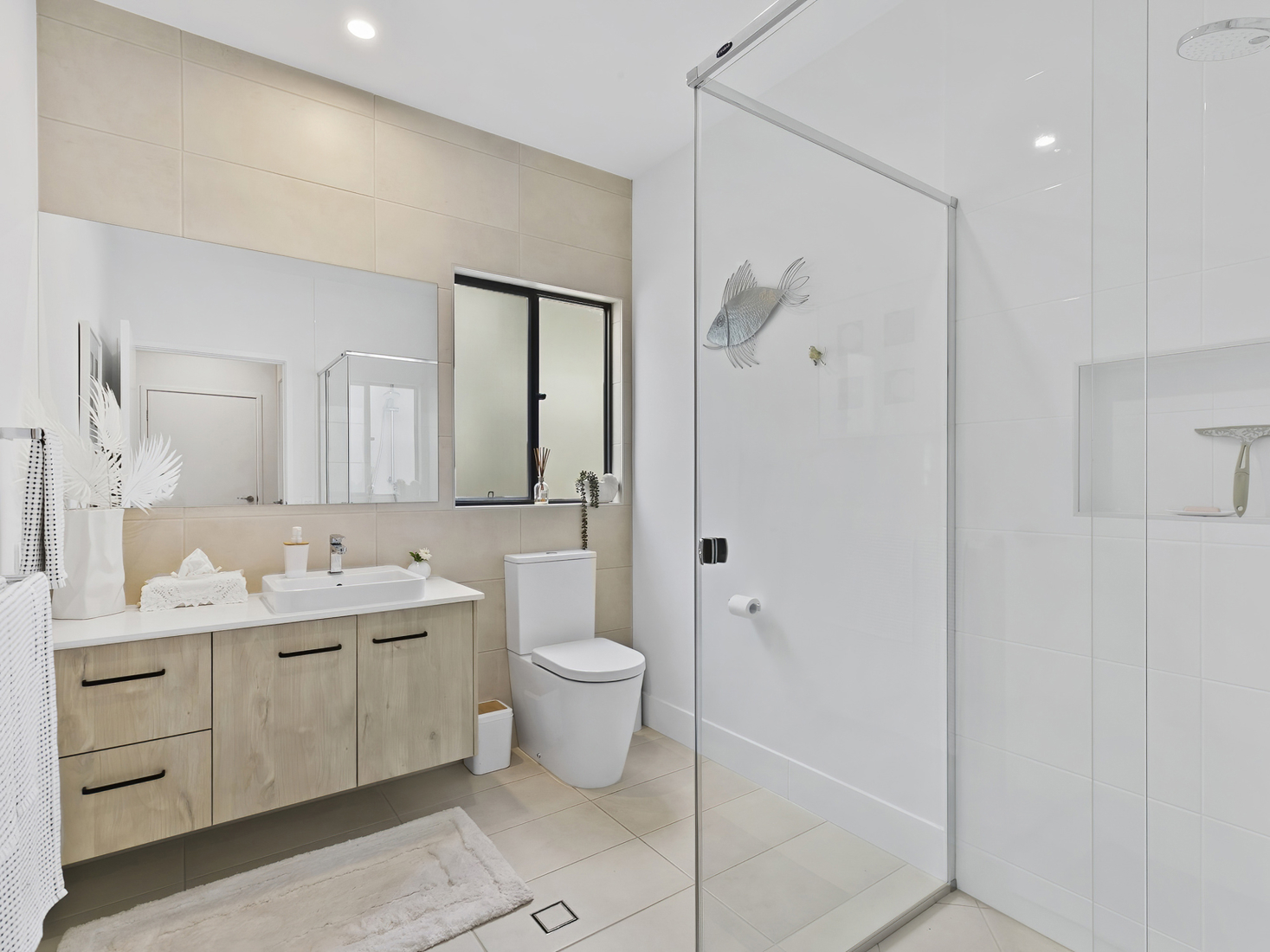 modern bathroom with beige floor and wall tile, corner shower and black hardware.