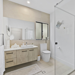 modern bathroom with beige floor and wall tile, corner shower and black hardware.