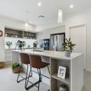 interior image of a modern white kitchen with tan bar stools and plant accents