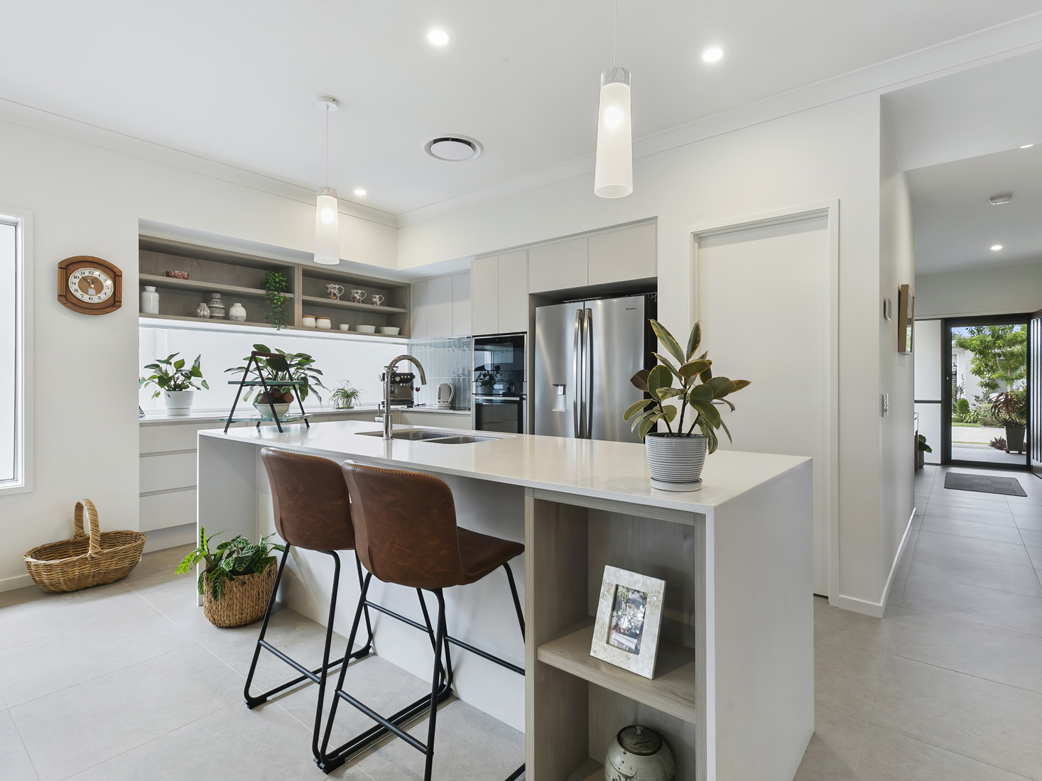 interior image of a modern white kitchen with tan bar stools and plant accents