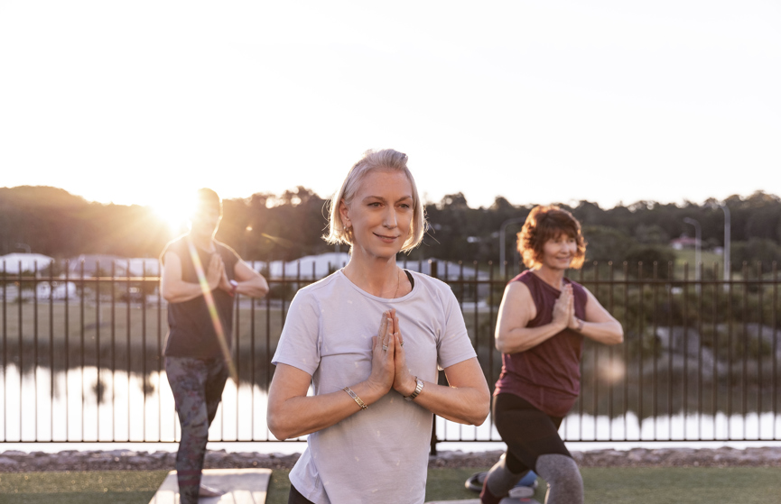 Group of ladies performing yoga outdoors with sunset in background