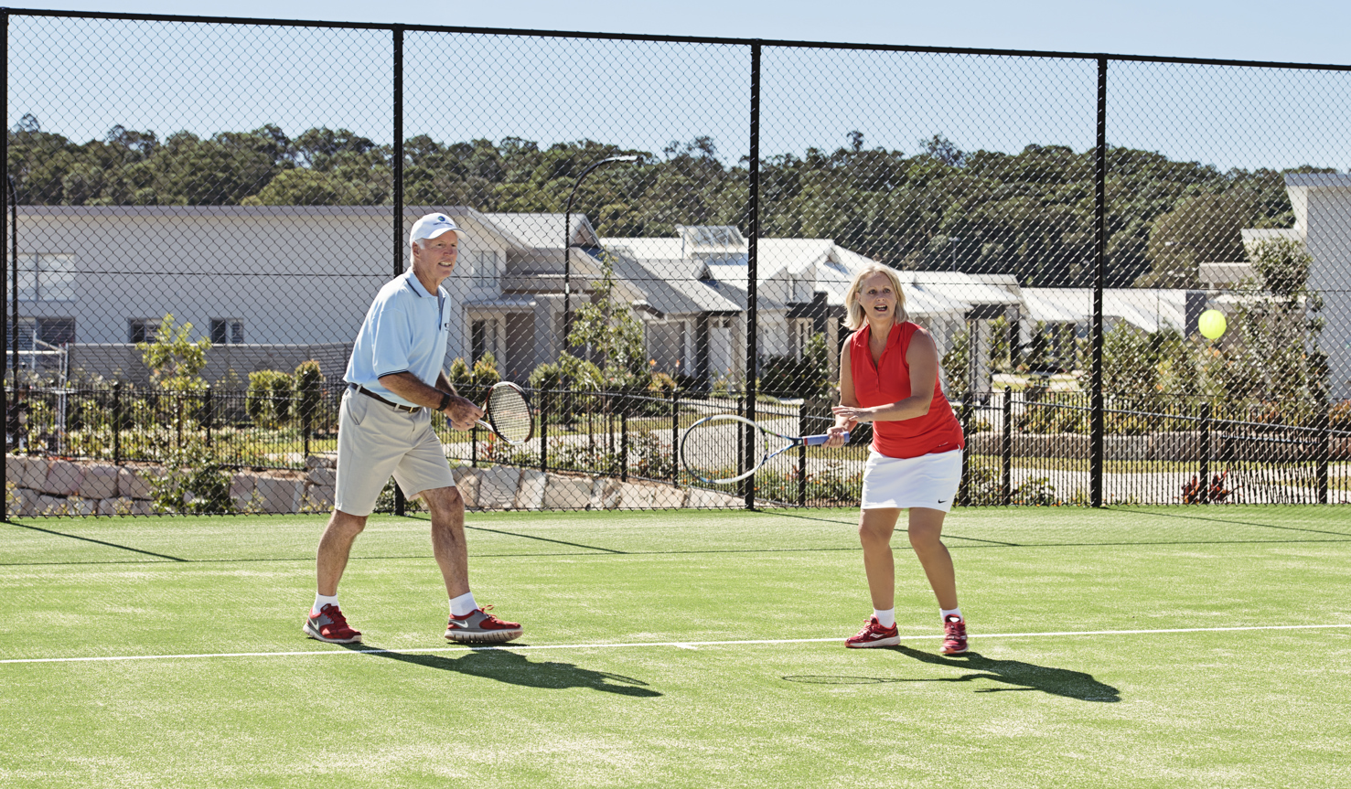 Two homeowners playing tennis on the Halcyon Lakeside tennis court