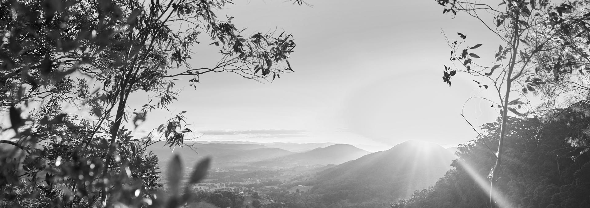 black and white image of a landscape overlooking mountainous region at sunset