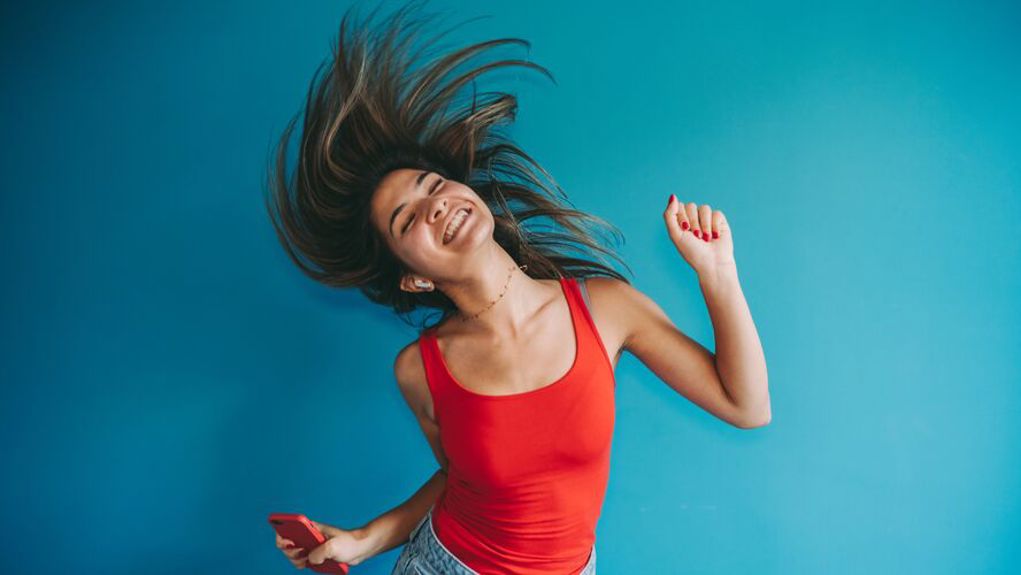 Happy young woman wearing a red top, with a blue background