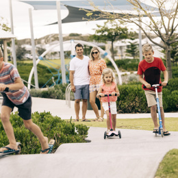 Kids riding scooters along path near park