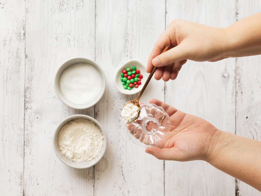 Ingredients for Christmas DIY cookie mix tree ornament including mini M&Ms, baking powder, egg, and butter.