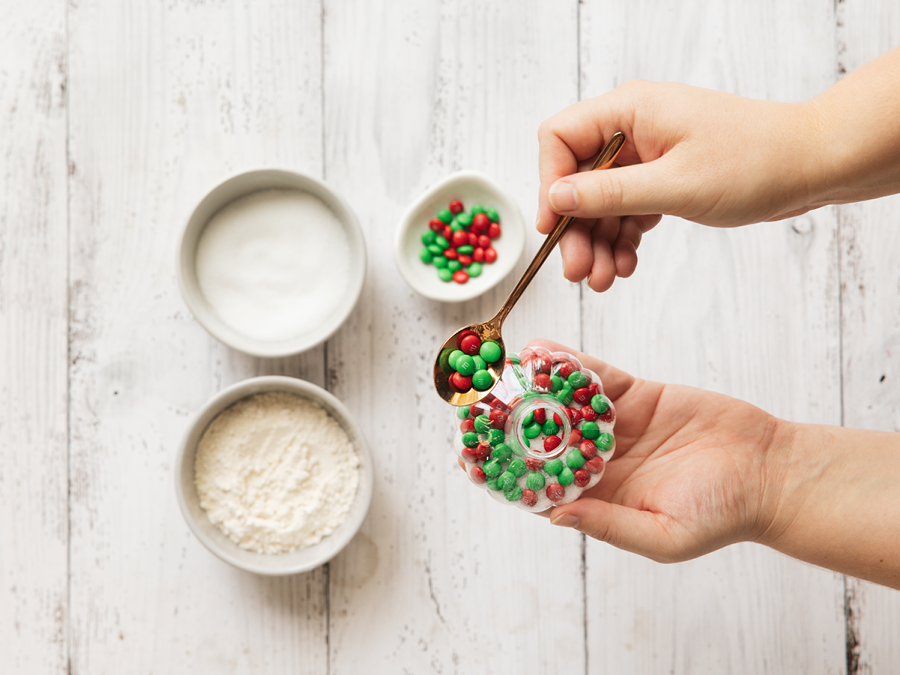 Ingredients for Christmas DIY cookie mix tree ornament including mini M&Ms, baking powder, egg, and butter.