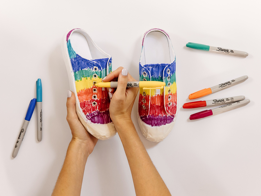 Hands colouring in sneakers with coloured permanent marker pens