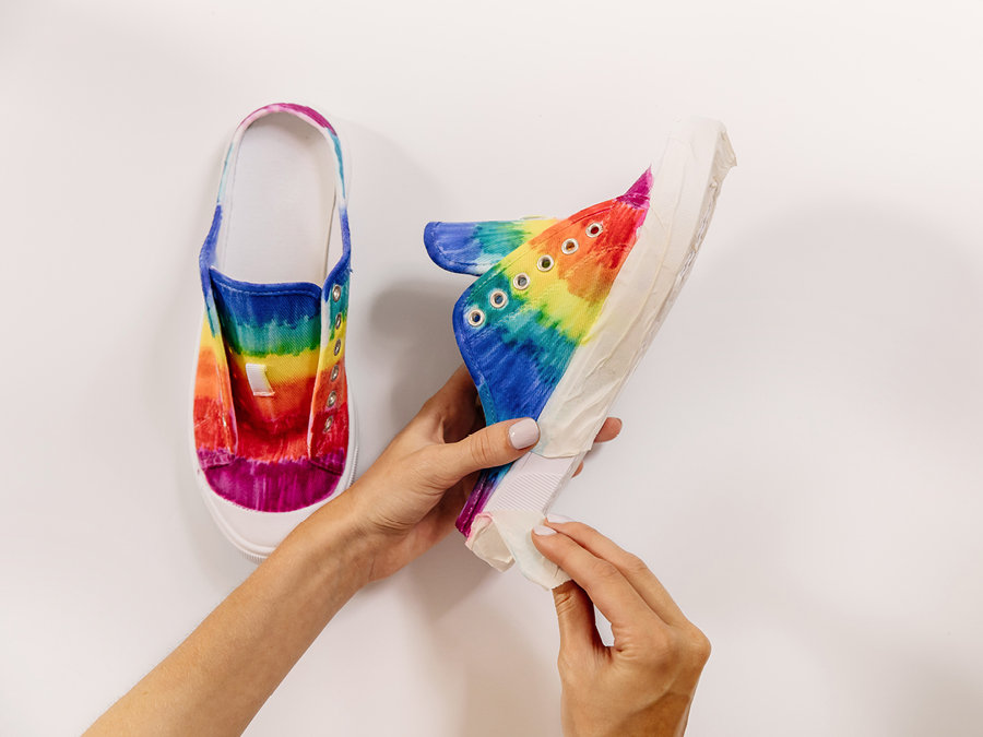 Hands removing masking tape from side of sneakers