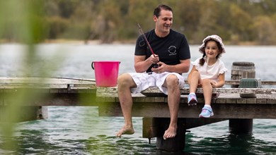 Father and daughter sitting on a jetty fishing