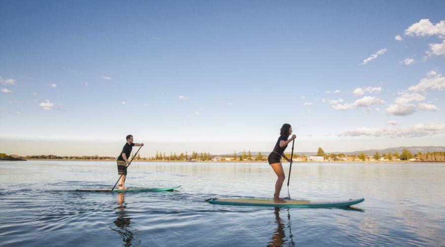 Man and woman stand up paddle boarding on Lake Illawarra