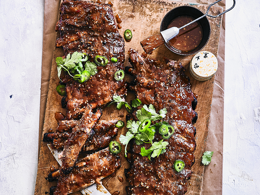 Spiced marinated miso BBQ ribs sliced and served on a wooden chopping board. 