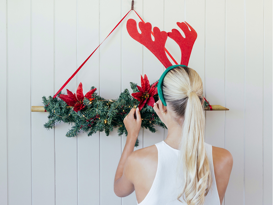 A young woman hanging up a DIY Christmas Advent calendar on the wall.