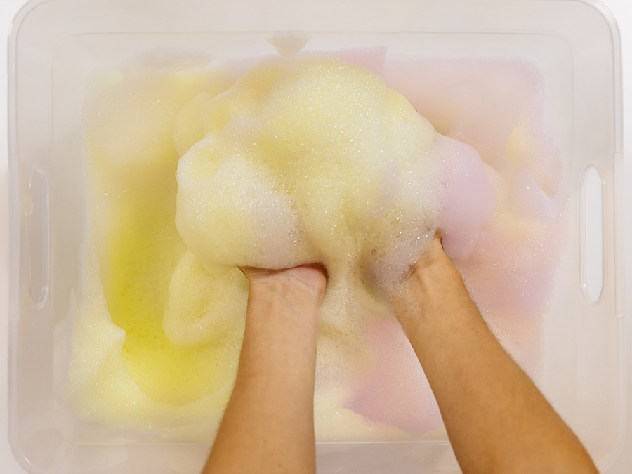 Multi-coloured rainbow soap bubbles in a plastic tub