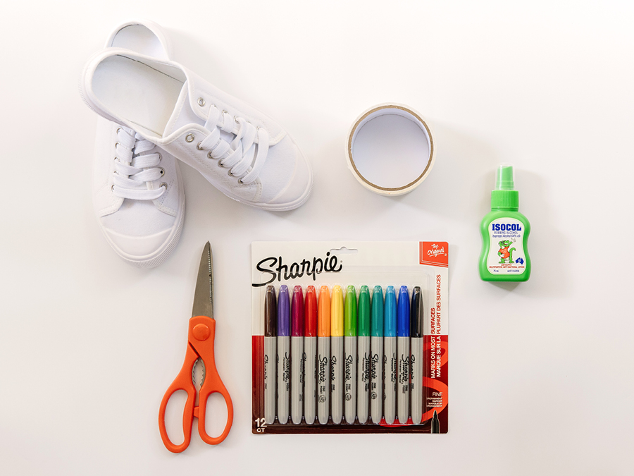An assortment of craft items including scissors, coloured sharpie pens, glue, masking tape, and white sneakers