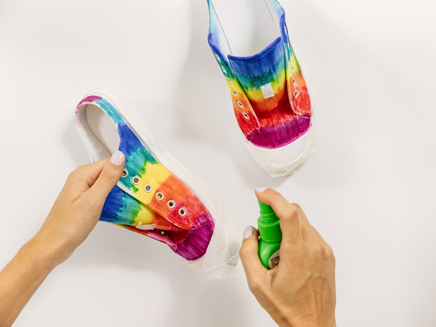 Coloured white sneakers being sprayed with setting spray