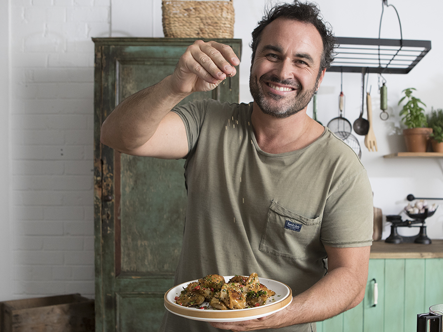 Miguel Maestre sprinkling sesame seeds on his potstickers in the kitchen.