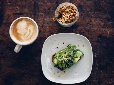 Smashed avocado on toast with coffee and breakfast bowl