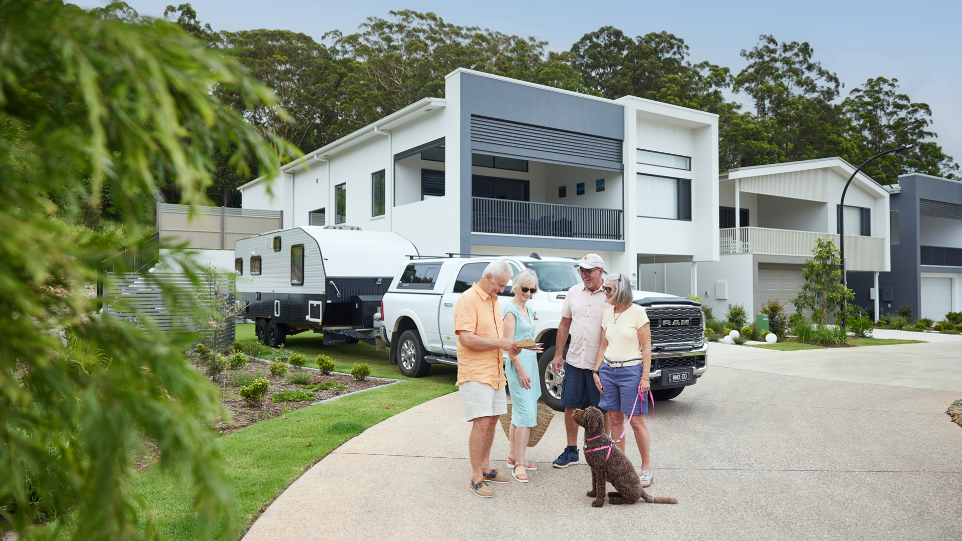 Couple meets with friends to discuss road trip, with their caravan packed and dog ready for their next adventure