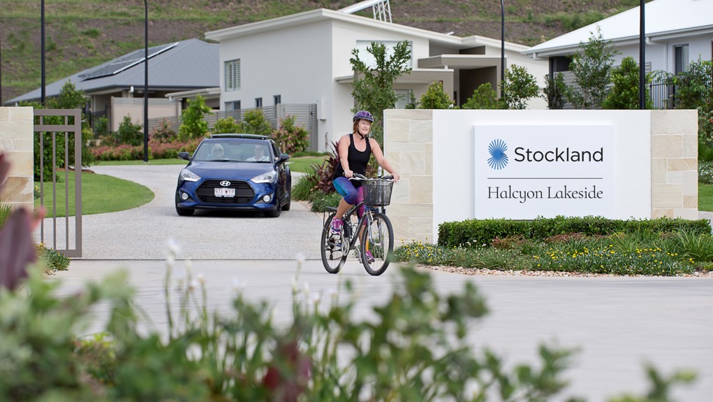 Halcyon Lakeside front gate entry to community, with car leaving and lady riding bicycle