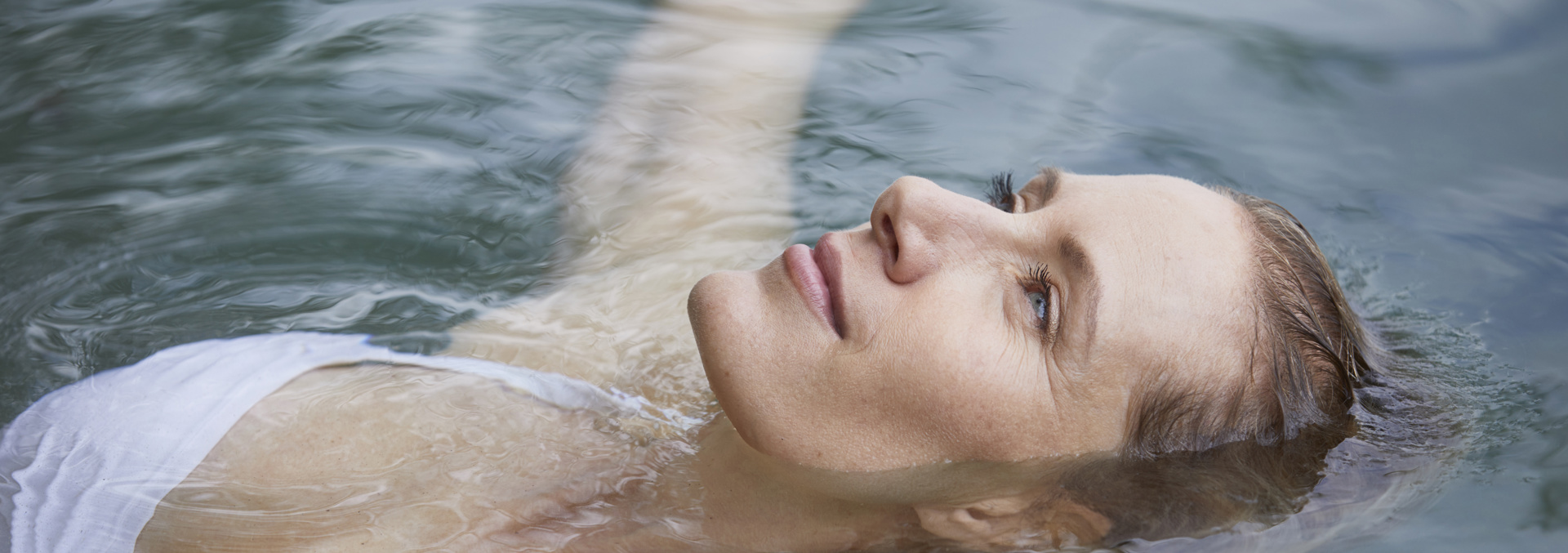 Lady floating on back in pool, looking relaxed